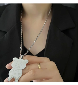 Detailed view of silver bear pendant necklace with superstar engraving on black suit