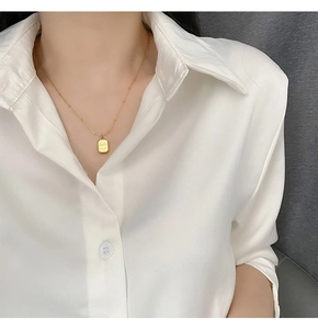 Detailed view of a gold smile rectangular pendant on a delicate beaded chain necklace