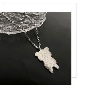 Macro detail of silver bear pendant with engraved Super Star text on a sleek chain