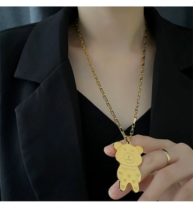 Detail of a golden bear necklace with super star engraving on a black suit backdrop
