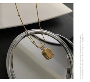 Macro detail of gold smile pendant necklace reflected on mirror with beaded chain design