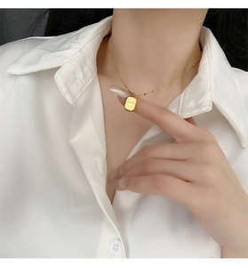Detail of gold-plated necklace with Smile engraved rectangular pendant worn by a model