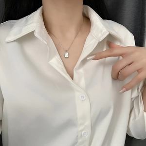 Minimalist silver bead chain necklace with rectangular shell pendant worn on white satin