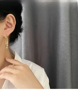 Close-up of elegant gold bamboo hoop earrings and matching ring worn by a model