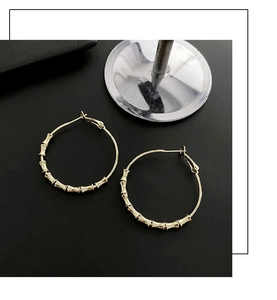 Close-up of golden bamboo texture hoop earrings with polished metal finish