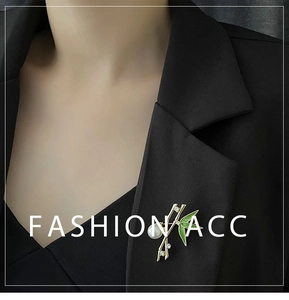 Detail of bamboo brooch with green enamel and pearl on a black suit lapel
