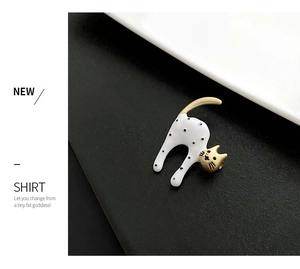 Detailed close-up of a creative white cat brooch with black dots and gold metal tail