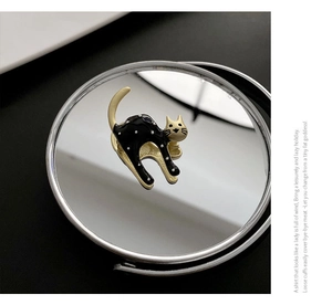 Detail of jumping cat brooch with black enamel, white polka dots and gold edges