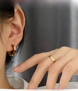 Detailansicht von Goldreifenohrringen mit Zirkonia und einem schlichten Ring am Model