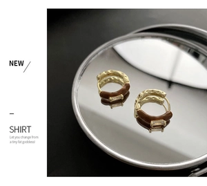 Details von Vintage-Goldohrringen mit braunem Emaille und Zirkonia auf einem Spiegel