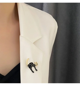 Close-up of a stylish black and white polka dot cat brooch pinned on a white blazer lapel