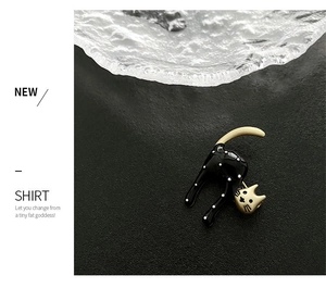 Detailed close-up of a cute black cat enamel brooch with white polka dots and gold accents