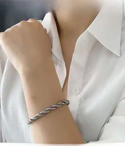 Detail of twisted silver titanium steel bracelet with purple accents worn on a wrist