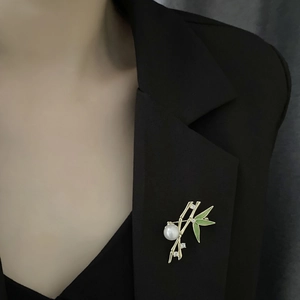 Elegant bamboo brooch with green enamel and pearl on black blazer lapel for women