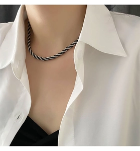Detailed view of a black and white twisted cord necklace with a sleek metal ring clasp