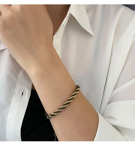 Detail of twisted rope bracelet in 18K gold and black on a model's wrist