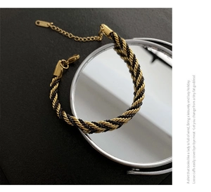 Close-up of gold and black twisted rope chain bracelet with lobster clasp and extender