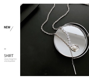 Détail d'un long collier de perles avec diamants pavés sur miroir noir poli