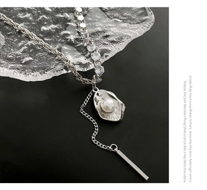 Détail du sautoir argenté avec perle, pendentif coquillage et accents de zircons