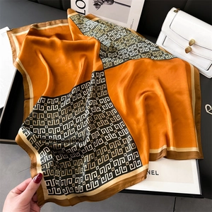 Detail of luxury orange satin square scarf with geometric pattern and silky texture