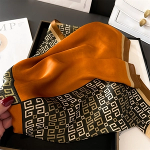 Detail of burnt orange and Greek Key geometric pattern on luxury silk scarf texture
