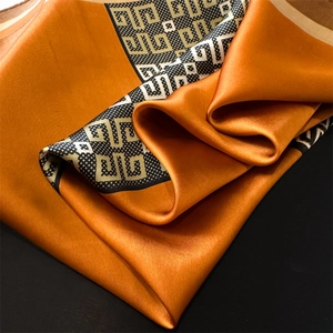 Macro detail of luxury orange silk scarf featuring geometric patterns and glossy texture