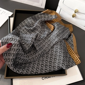 Detail of silk-feel scarf with black-white geometric patterns and mustard yellow border