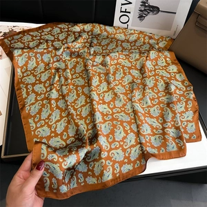 Detailed macro view of orange paisley silk scarf texture with hand-rolled edges