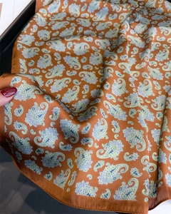 Close-up of vintage orange silk scarf featuring detailed paisley patterns and smooth texture