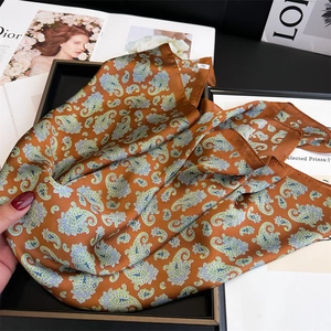 Close-up of bronze paisley silk scarf with intricate vintage patterns and silky texture