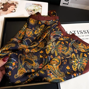 Detail of vintage paisley silk scarf with navy blue and orange patterns on a tray