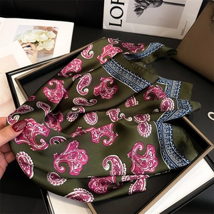 Detail of green paisley silk scarf with glossy satin texture and geometric borders