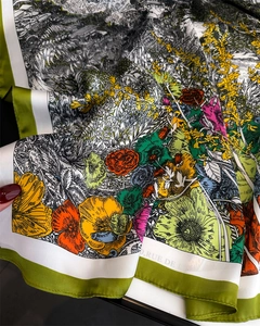 Detail eines bunten Seidenquadrats mit lebhaftem Blumenmuster und grünem Randabschluss