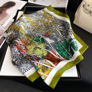 Detail eines Seidenquadrat-Halstuchs mit Blumenmuster und grünem Rand auf Modetablett
