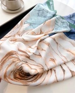 Detail of silk-like scarf with abstract marble texture next to a coffee cup