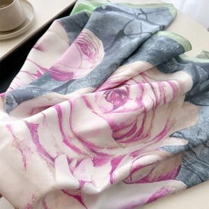 Luxurious 90cm silk scarf featuring pink rose patterns on a creamy tabletop setting