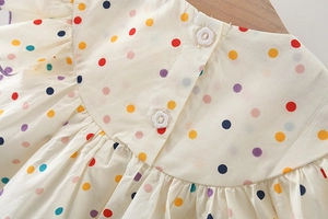 Dettaglio di bottoni a forma di fiore e tessuto a pois sul retro del vestito bimba