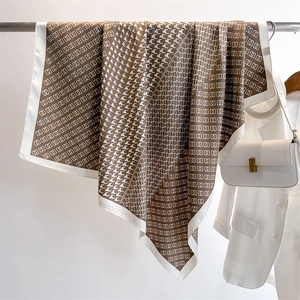 Dettaglio di un foulard di seta marrone con motivi a catena bianca e stampa pied de poule