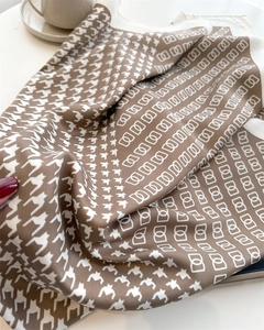 Dettaglio della trama del foulard in seta marrone con stampa pied-de-poule e fibbie