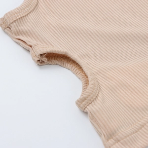 Close-up of beige rib-knit fabric texture and neat edge stitching on girl's tank top