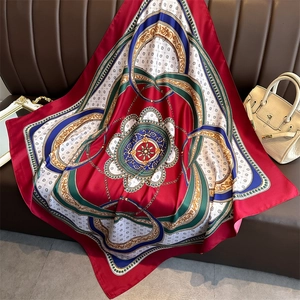 Detailed shot of a red luxury satin scarf with vintage chain patterns on a leather sofa