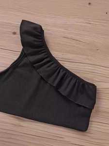 Top a costine nero da bambina con volant asimmetrici e design monospalla alla moda