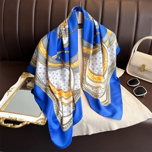 Close-up of elegant silk scarf with blue chain pattern draped over beige shirt