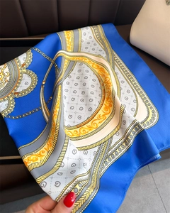 Close-up of a blue satin scarf featuring gold chain and classical floral patterns
