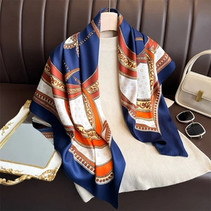 Elegant 90cm navy and orange chain pattern silk scarf styled on a beige knit sweater