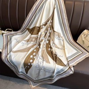 Détail d'un foulard en soie avec motif muguet posé sur un fond en cuir brun