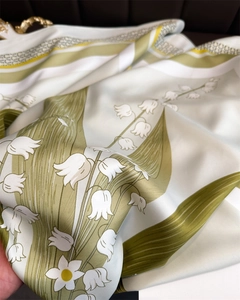 Détail d'un foulard en soie avec motif muguet et texture de tissu délicate et brillante
