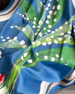 Détail d'un foulard en soie avec imprimé muguet et motif géométrique de bordure
