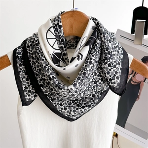 Élégant foulard carré en satin à fleurs noir et blanc sur un cintre en bois