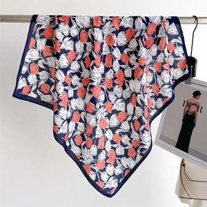 Detail of hanging silk scarf featuring orange tulip prints and navy blue border contrast
